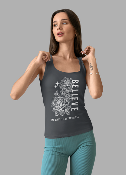 Woman wearing a gray tank top with a graphic design and teal shorts on a gray background