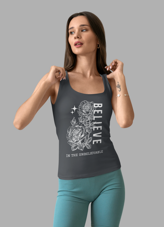 Woman wearing a gray tank top with a graphic design and teal shorts on a gray background
