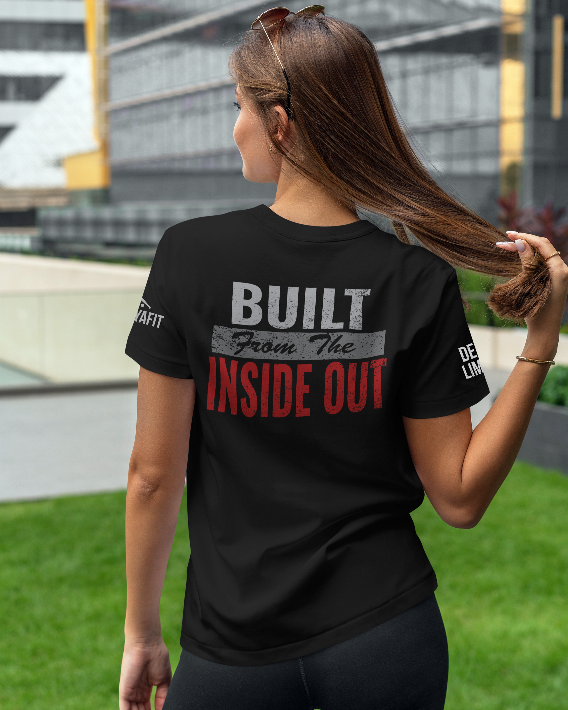 Woman wearing a black t-shirt with 'BUILT FROM THE INSIDE OUT' text, standing outdoors.