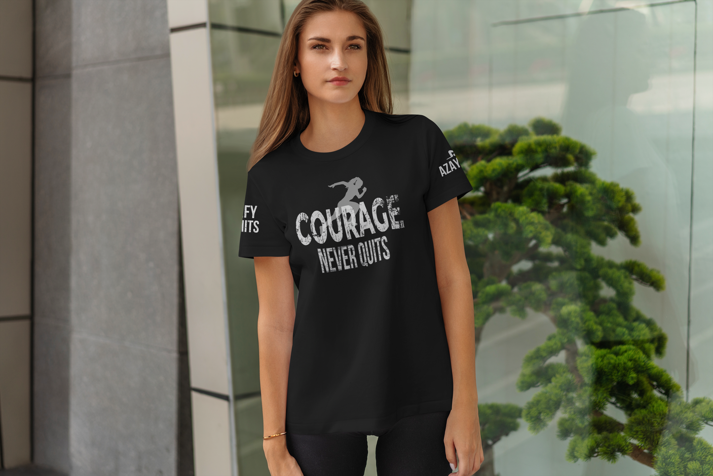 Woman wearing a black t-shirt with 'Courage Never Quits' text, standing outdoors.