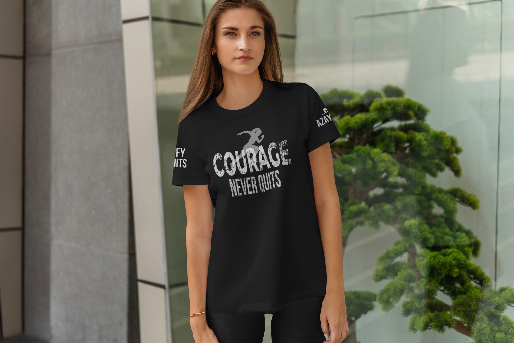 Woman wearing a black t-shirt with 'Courage Never Quits' text, standing outdoors.