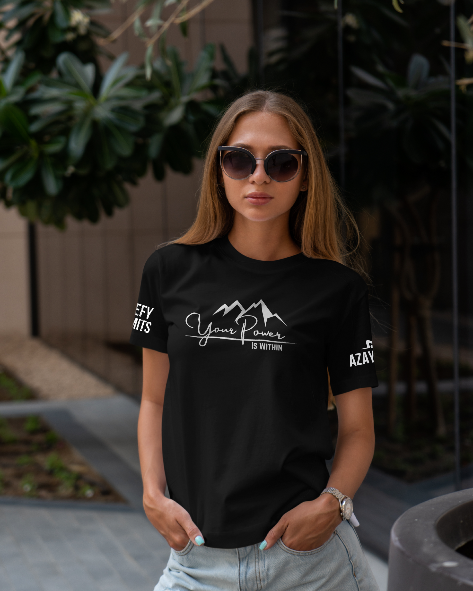 Woman wearing a black t-shirt with white text and graphics outdoors.