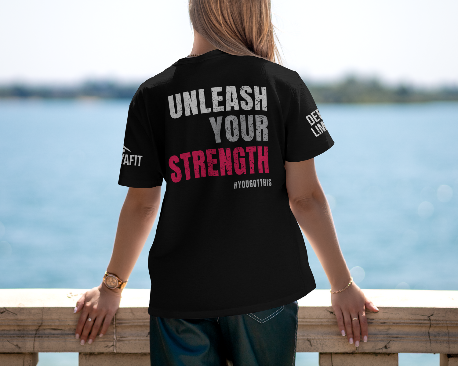 model wearing black unleash your strength tee looking over a bridge