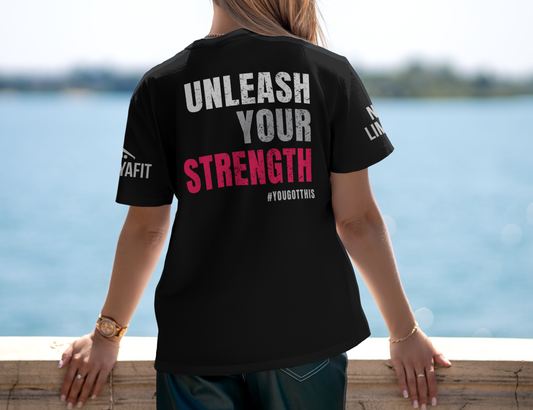 Person wearing a black t-shirt with motivational text by a body of water