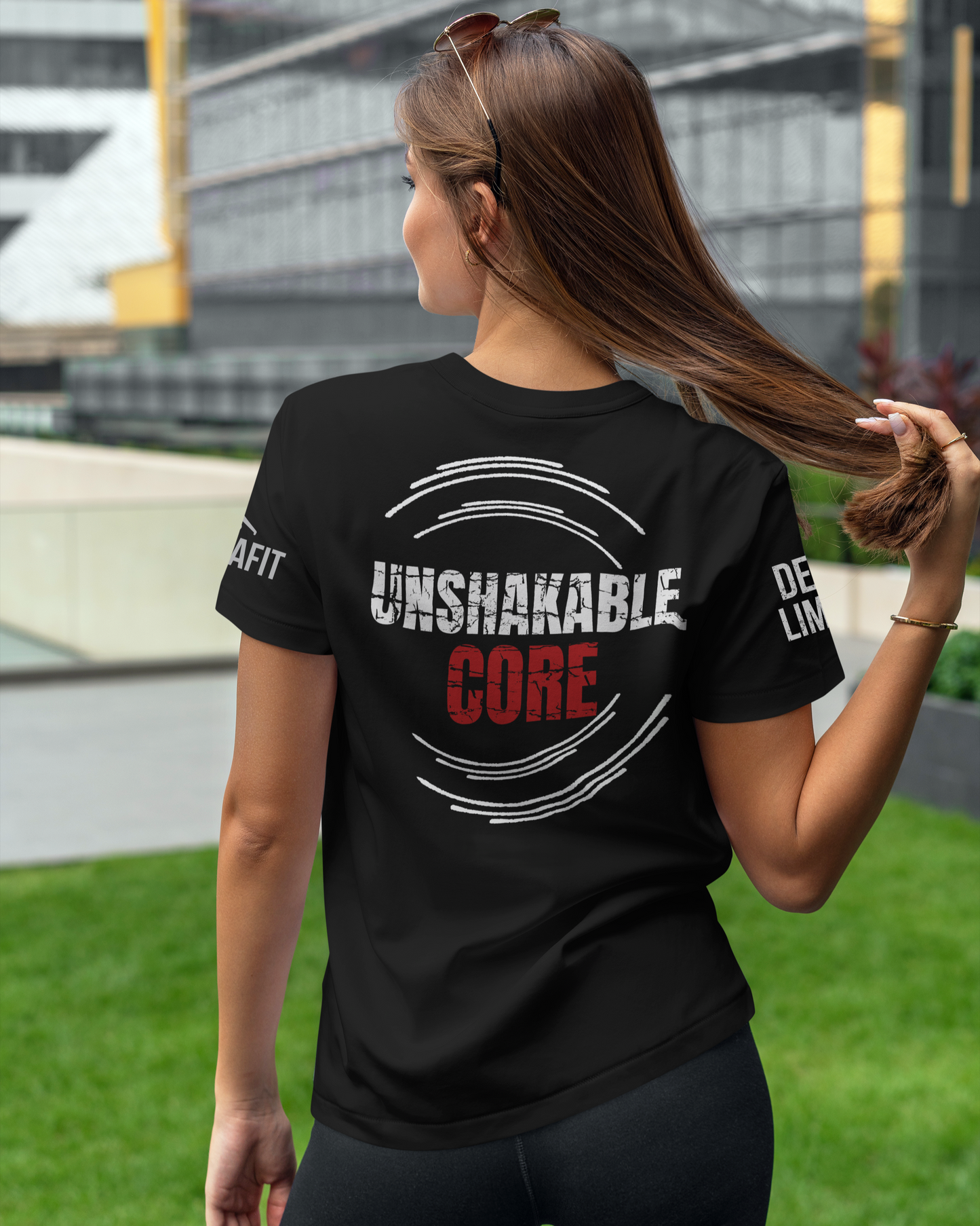 Woman wearing a black t-shirt with 'Unshakable Core' text outdoors.