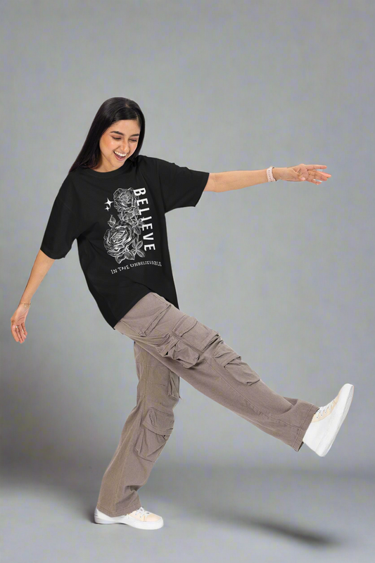 Cheerful woman having fun in a studio while wearing a black Believe in the Unbelievable unisex T-shirt. This soft, comfortable tee inspires confidence and positivity, perfect for casual and active wear.