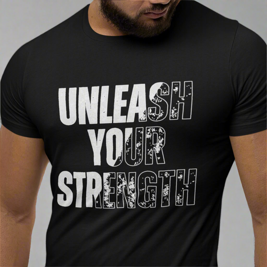 Cropped image of a man wearing a black T-shirt with the "Unleash Your Strength" design in bold black and white lettering. The close-up shot highlights the powerful message and details of the design.