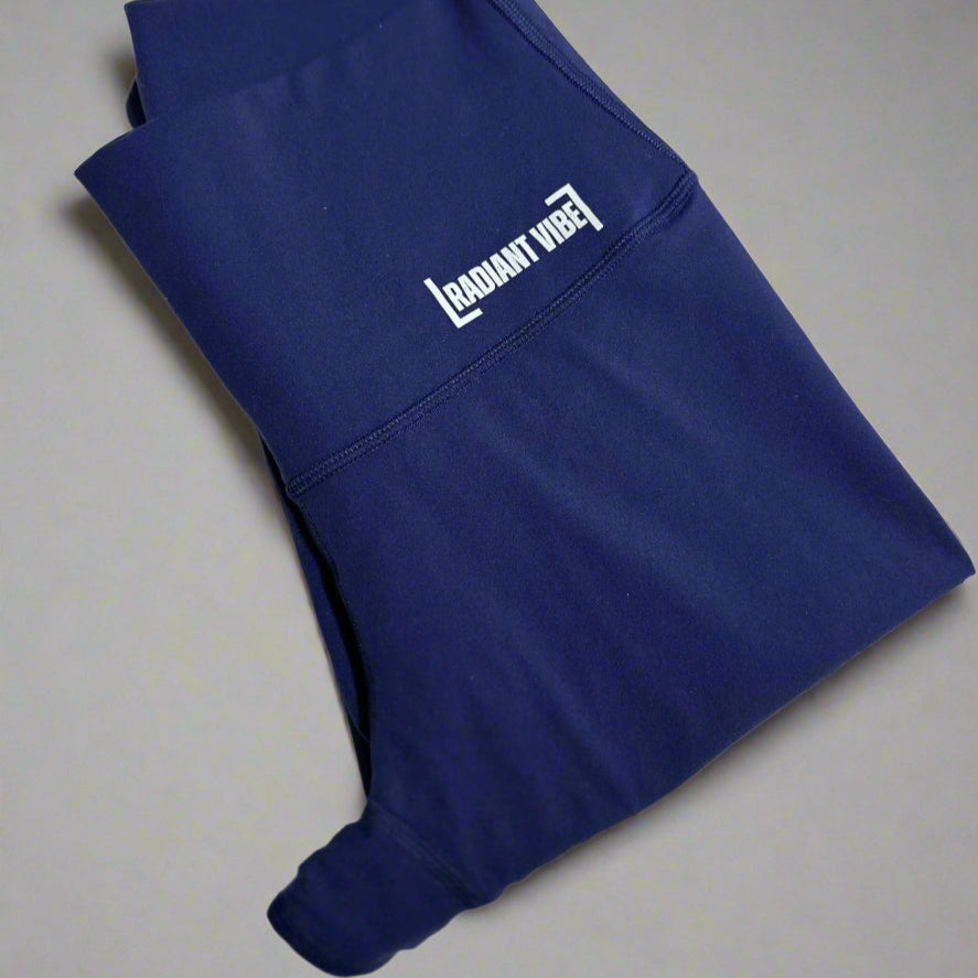  Close-up of folded blue leggings showcasing "Radiant Vibe" in small white print on the front hip. Designed for comfort and performance, these leggings offer a sleek and stylish fit for active lifestyles.