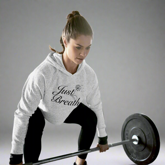 Woman lifting weights while wearing a heather grey crop hoodie, designed for comfort, style, and performance during workouts.