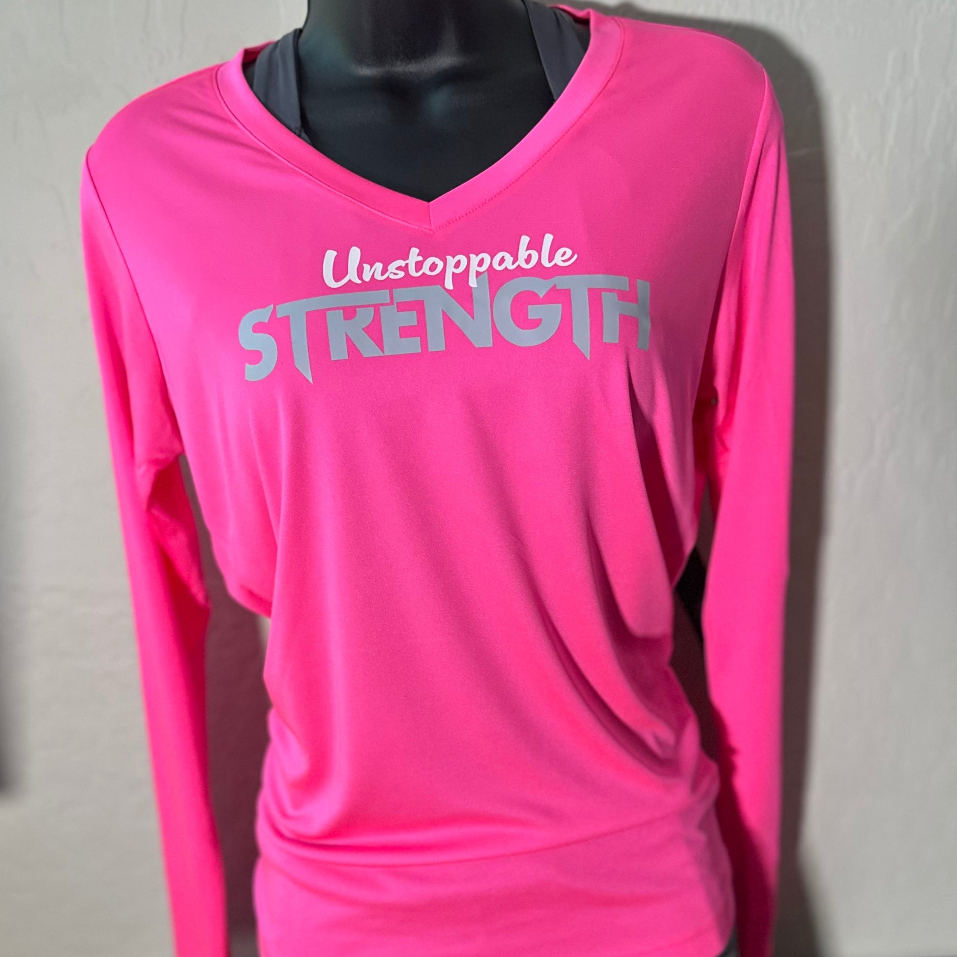 Hot pink Unstoppable Strength long sleeve performance top displayed on a mannequin, showcasing its design and fit.