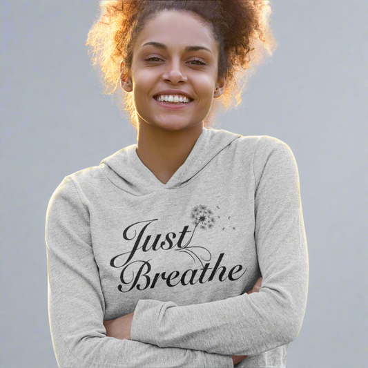 Happy woman posing with her arms crossed while wearing the heather grey Just Breathe crop hoodie, a stylish and comfortable choice for casual wear and workouts.