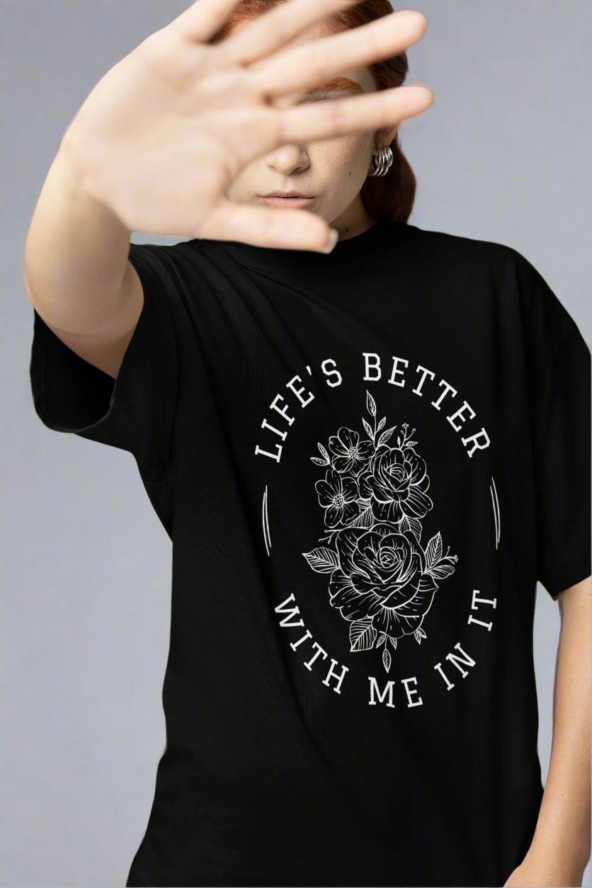 Woman covering her face in a studio while wearing the Life Is Better With Me In It T-shirt, highlighting its uplifting message and relaxed fit.
