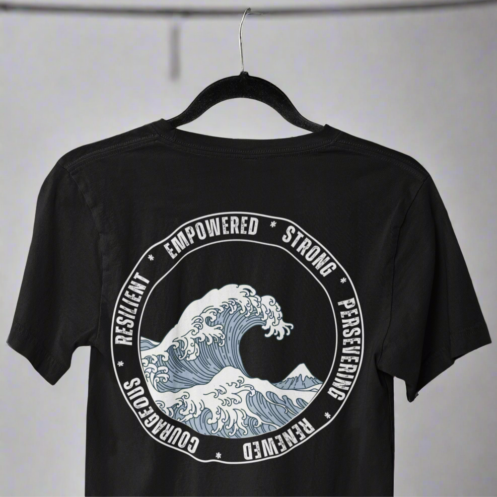 Back view of the Wave of Strength T-shirt displayed on a hanger, featuring a wave design surrounded by the words "Resilient, Empowered, Strong, Renewed, and Courageous," symbolizing inner strength and perseverance.