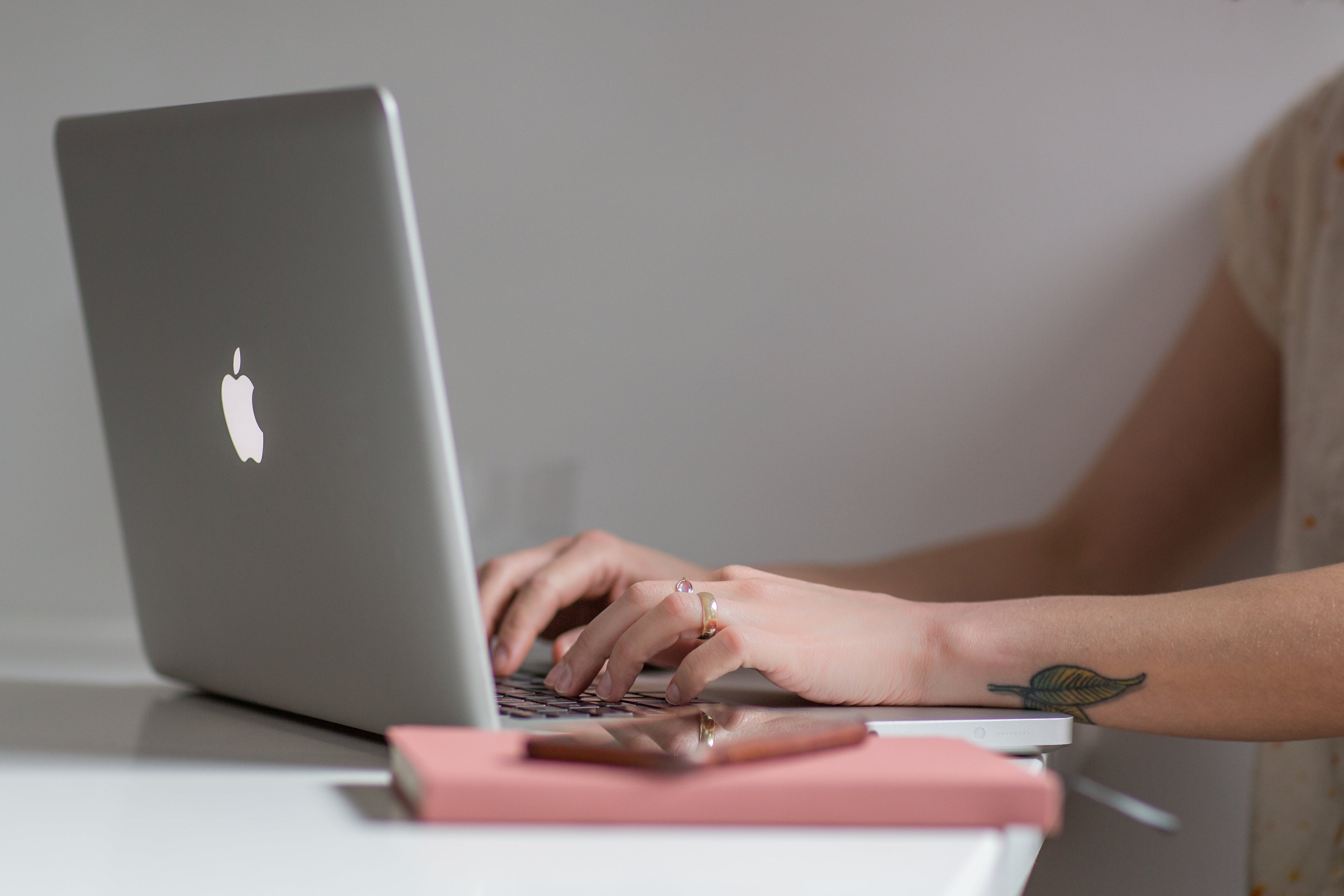 Person using a laptop with an Apple logo on a desk